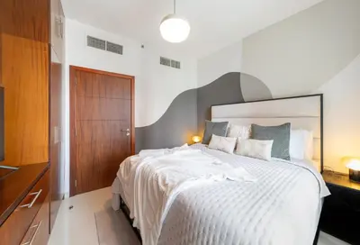 a bedroom with a large white bed and a wooden door at EDEN'S Homes & Villas - Standpoint Residences in Dubai
