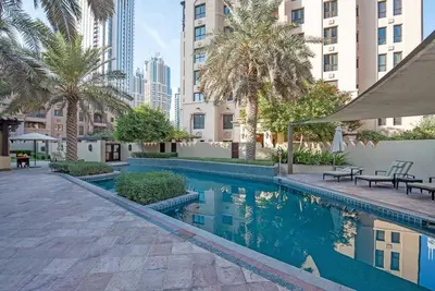 a swimming pool with palm trees and buildings at Stylish 2BR with Balcony Near Dubai Mall and Burj Khalifa in Dubai