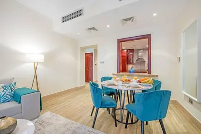 a living room with a table and blue chairs at Stylish 2BR with Balcony Near Dubai Mall and Burj Khalifa in Dubai