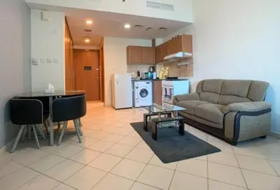 a living room with a couch and a table at Cozy Furnished Studio in Dubai