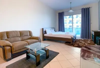 a living room with a couch and a bed at Cozy Furnished Studio in Dubai