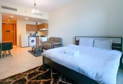 a bedroom with a large bed and a kitchen at Cozy Furnished Studio in Dubai