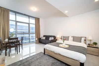 a bedroom with a large bed and a dining room at Furnished Cozy Studio in Dubai
