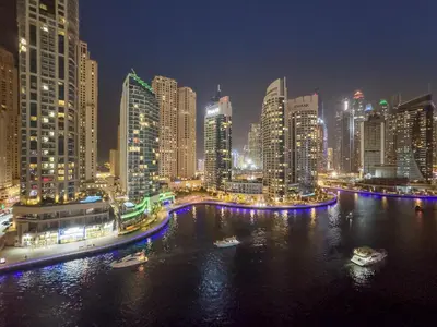 a city skyline at night with boats in the water at FIRST CLASS 2BR with Exquisite Full Marina View in Dubai