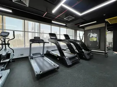 a gym with several treadmills in a room with windows at Stylish Studio Walk to Dubai Mall & Burj Khalifa with Pool, Gym & Balcony in Dubai