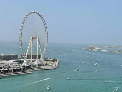 a ferris wheel in the water next to a city at Amazing Sea View 2 bedroom Full Apartment in Dubai