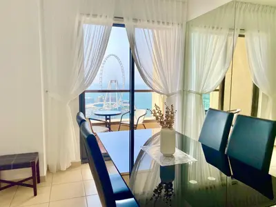 a dining room with a glass table and a view of a wheel at Amazing Sea View 2 bedroom Full Apartment in Dubai