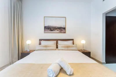 a bedroom with a large white bed with two lamps at Stylish 1 BR in The Medalist by PK Holidays in Dubai