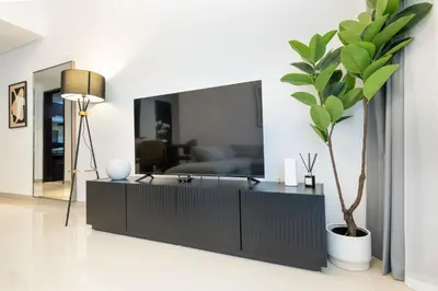 a living room with a black dresser and a potted plant at Stylish 1 BR in The Medalist by PK Holidays in Dubai