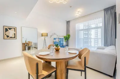 a dining room and living room with a table and chairs at Stylish 1 BR in The Medalist by PK Holidays in Dubai