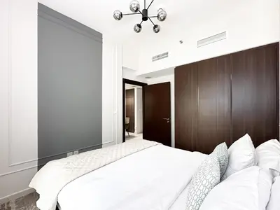 a bedroom with a large bed with a wooden headboard at Trophy - Blossom Suites w Balcony Garden & Canal View in Dubai