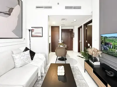 a living room with a white couch and a table at Trophy - Blossom Suites w Balcony Garden & Canal View in Dubai