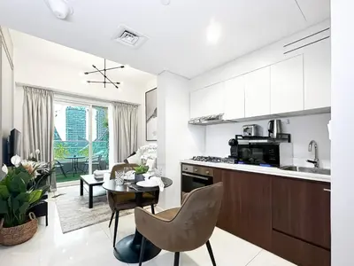 a kitchen and living room with a table and chairs at Trophy - Blossom Suites w Balcony Garden & Canal View in Dubai