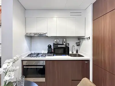 a kitchen with white cabinets and a sink and a microwave at Trophy - Blossom Suites w Balcony Garden & Canal View in Dubai