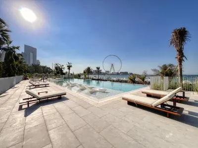 a swimming pool with chaise lounges and a ferris wheel at Remarkable 2BR+storage in JBR with Sea View in Dubai