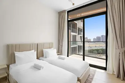 two beds in a hotel room with a large window at Stunning modern 3BR apartment in JVC in Dubai