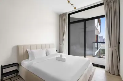 a bedroom with a large white bed and a large window at Stunning modern 3BR apartment in JVC in Dubai