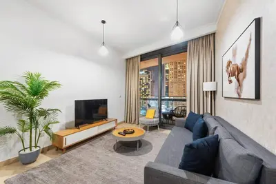 a living room with a blue couch and a tv at FIRST CLASS 1BR Beautifully Furnished in Dubai