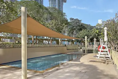 a swimming pool with a tan umbrella and a ladder at FIRST CLASS 1BR Beautifully Furnished in Dubai