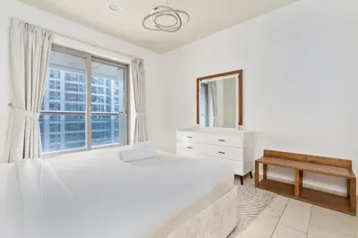 a white bedroom with a large bed and a window at Ahlan HH - Princess Tower - Elegant 1BR in Dubai Marina in Dubai