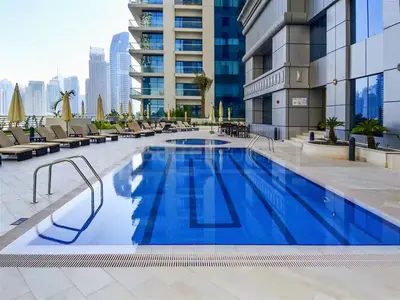 a large swimming pool with chairs and a building at Ahlan HH - Princess Tower - Elegant 1BR in Dubai Marina in Dubai