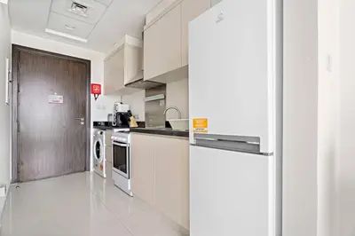 a kitchen with white cabinets and a refrigerator at StoneTree - Modern Studio - Carson A in Dubai