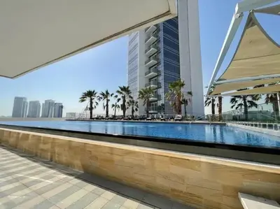 a swimming pool with palm trees and a tall building at StoneTree - Modern Studio - Carson A in Dubai