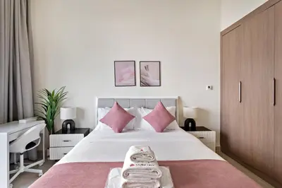 a bedroom with a large bed with pink pillows at Cozy Studio in Al Furjan in Dubai