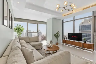 a living room with a large couch and a tv at High Floor Burj Khalifa & Sea View with stunning Infinity Pool in Dubai