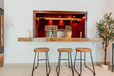 a kitchen with three bar stools at a counter at Stylish 2-Bedroom Escape near Dubai Mall in Dubai