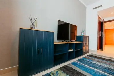 a living room with a blue cabinet and a tv at Stylish 2-Bedroom Escape near Dubai Mall in Dubai