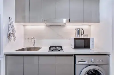 a white kitchen with a sink and a microwave at Tranquil Studio Retreat in Azizi 34 Near Downtown in Dubai