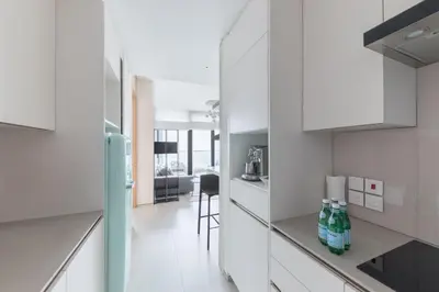 a white kitchen with white cabinets and a table at Fabulous 1BR apartment in Address Beach Resort in Dubai