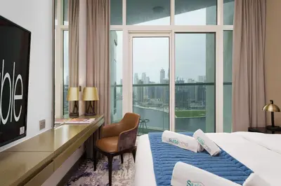 a hotel room with a bed and a desk and a window at Your Dream Home in Damac Maison Prive by Suiteable in Dubai