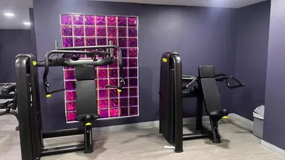 a gym with black equipment and purple walls at Newly renovated cosy studio in Dubai