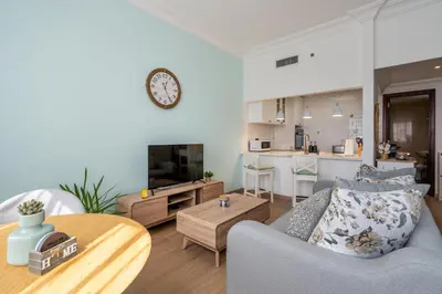 a living room with a couch and a clock on the wall at Newly renovated cosy studio in Dubai