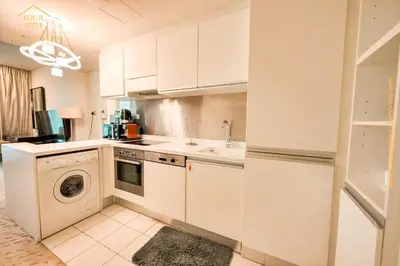 a kitchen with white cabinets and a washer and dryer at EMAAR Residences Fashion Avenue Full Burj Khalifa views Studio in Dubai