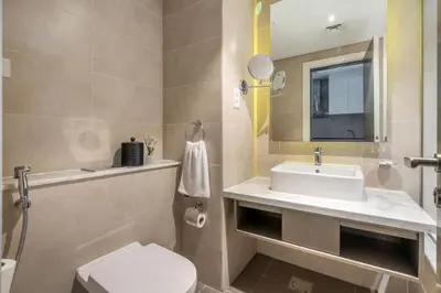 a bathroom with a sink and a toilet and a mirror at GuestReady - Modern studio with Dubai Canal View in Dubai
