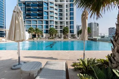 a swimming pool with two umbrellas and a building at GuestReady - Stylish studio with Dubai Canal view in Dubai