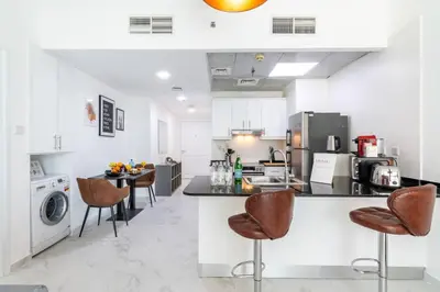 a kitchen with a counter and chairs in it at Stylish 1BR Apartment with City View Balcony Pool and Parking in Dubai