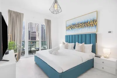 a bedroom with a large bed with a blue headboard at Stylish 1BR Apartment with City View Balcony Pool and Parking in Dubai