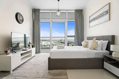 a bedroom with a large bed and a large window at Cozy Studio in Damac Hills in Dubai