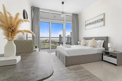 a white bedroom with a large bed and a couch at Cozy Studio in Damac Hills in Dubai