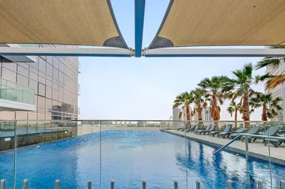 a view of a swimming pool in a building with palm trees at Cozy Studio in Damac Hills in Dubai