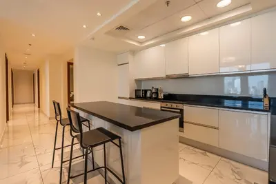a kitchen with white cabinets and black counter stools at Noora Tower I Habtoor City I Spacious 3BDR plus maid room I Business Bay in Dubai