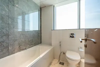 a bathroom with a toilet and a tub and a window at Noora Tower I Habtoor City I Spacious 3BDR plus maid room I Business Bay in Dubai