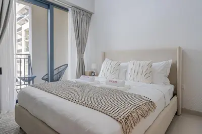 a bedroom with a large white bed with a balcony at Modern Brand New 1 BR Apartment in ZADA Tower in Dubai