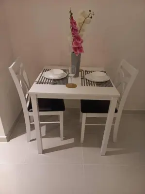 a white table with chairs and a vase with flowers at Furnished Studio in Damac Hills in Dubai