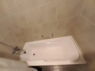a white tub in a bathroom with a tile wall at Furnished Studio in Damac Hills in Dubai