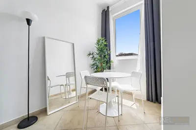 a dining room with a table and chairs and a mirror at WelHome - Stylish Studio with Park Views in Regent House 2 in Dubai